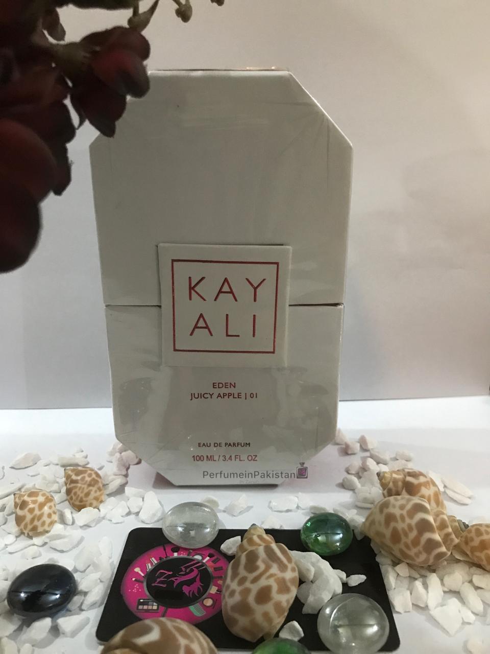 Kayali Eden Juicy Apple 01 Eau de Parfum 100ml unisex perfume box displayed with decorative shells and stones on a white background | Perfume in Pakistan