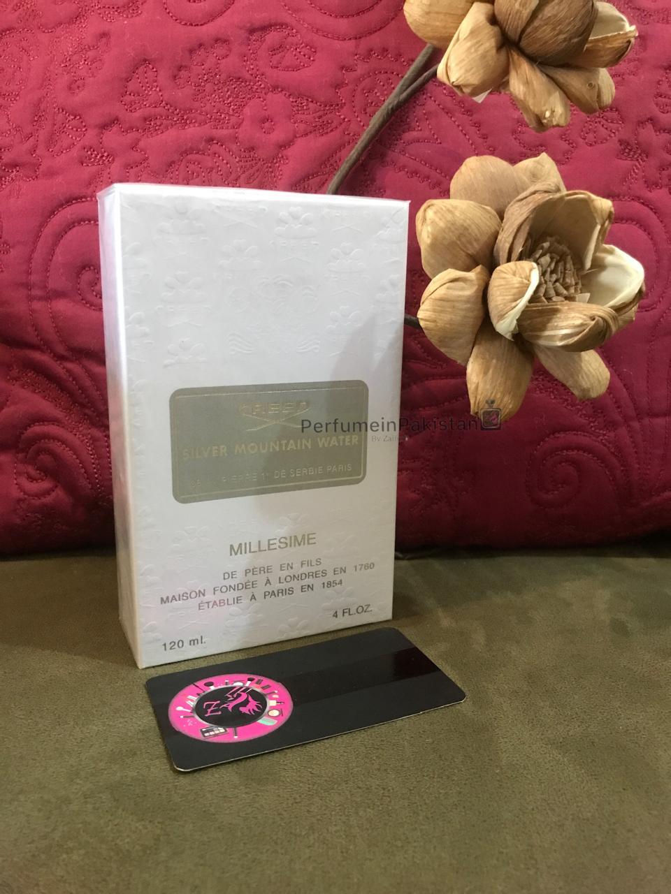 Creed Silver Mountain Water Millésime 120ml perfume box displayed with decorative wooden flowers and PerfumeinPakistan branding card