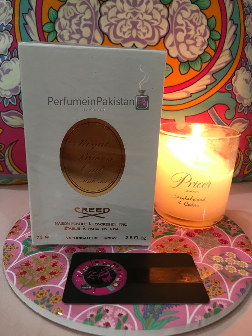 Creed Royal Princess Oud Millésime 75ml perfume box displayed with a decorative candle.