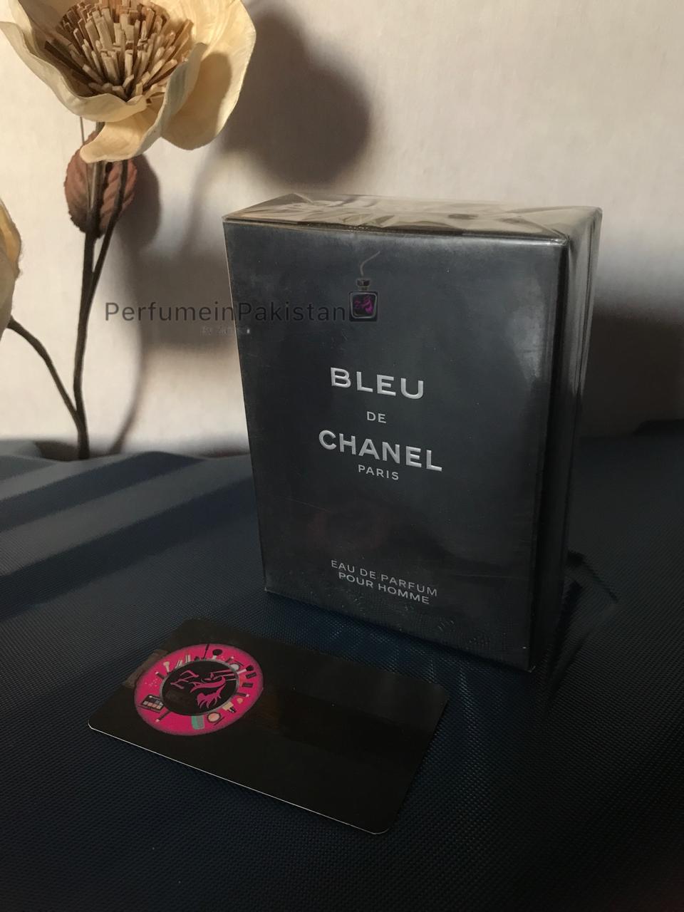 Bleu de Chanel Eau de Parfum 100ml men's perfume box displayed on a dark surface with decorative flowers and Perfume in Pakistan branding