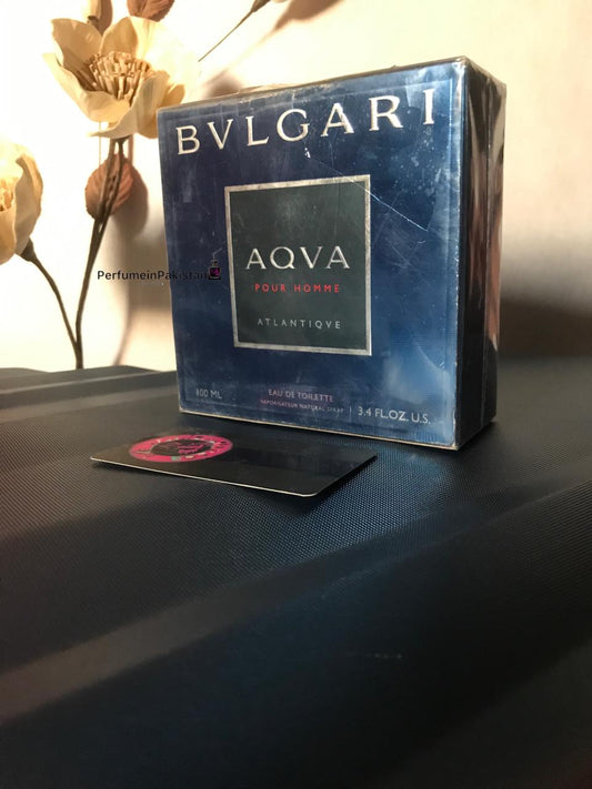Bvlgari Aqva Pour Homme Atlantique EDT 100ml men's perfume box displayed on a dark surface with decorative flowers and Perfume in Pakistan branding