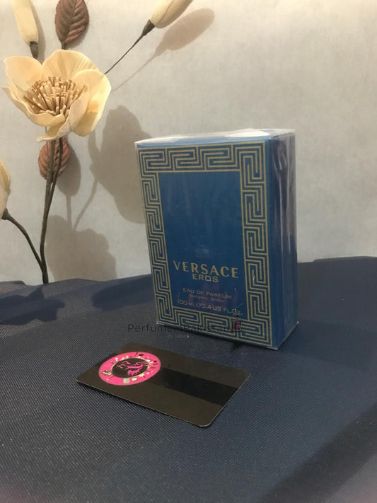 Versace Eros Eau de Parfum 100ml men's perfume box displayed on a dark surface with decorative flowers and Perfume in Pakistan branding