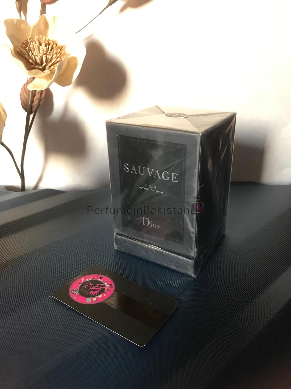 Dior Sauvage Elixir 90ml men's perfume box displayed on a dark surface with decorative flowers and Perfume in Pakistan branding