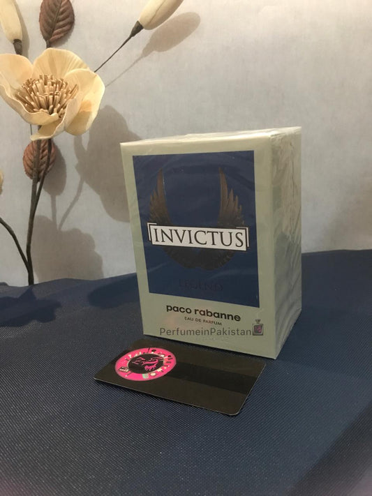 Paco Rabanne Invictus Legend Eau de Parfum 100ml men's perfume box displayed on a dark surface with decorative flowers and Perfume in Pakistan branding