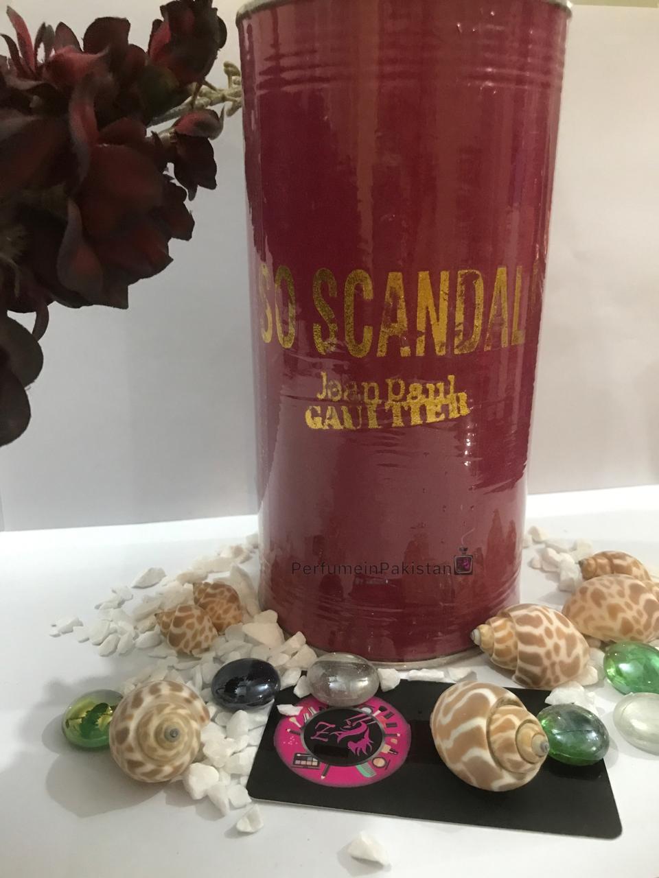 Jean Paul Gaultier So Scandal! Eau de Parfum perfume gift tin displayed with decorative shells, glass stones, and Perfume in Pakistan branding