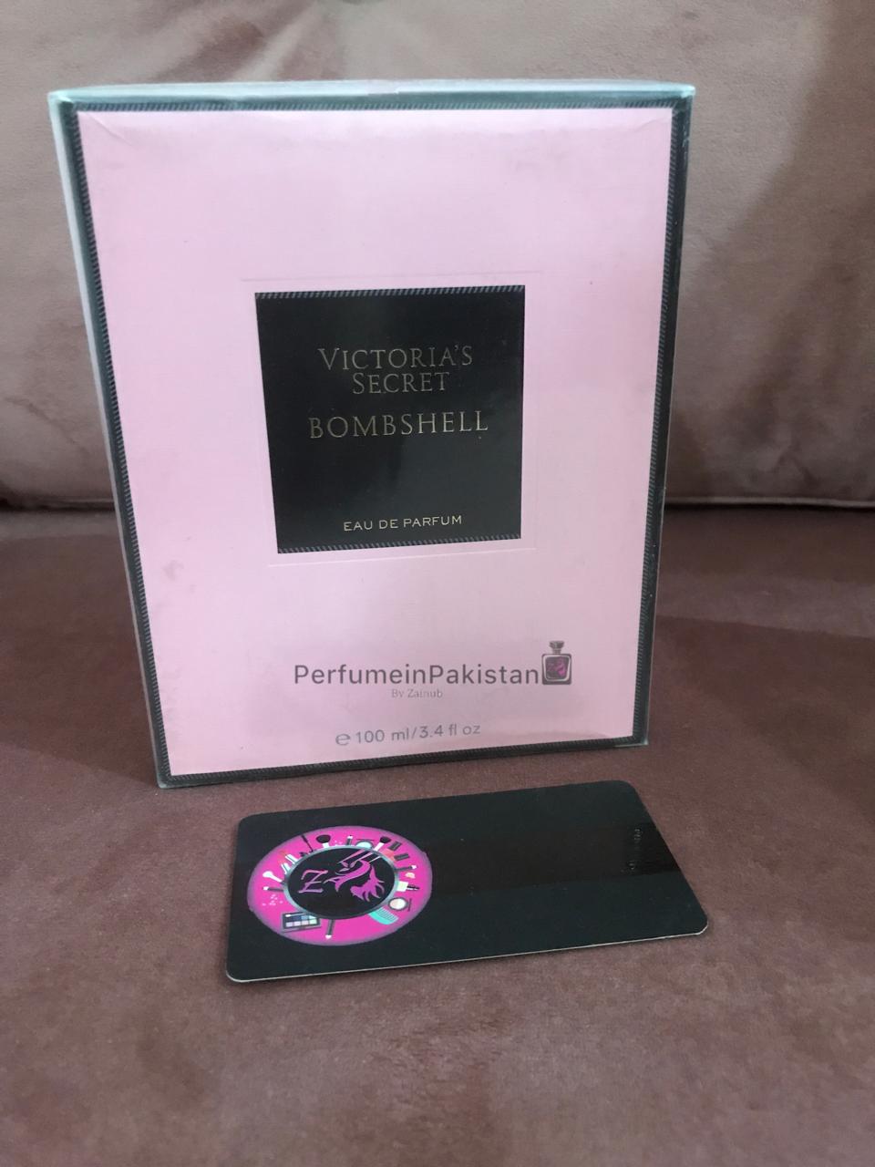 Victoria's Secret Bombshell Eau de Parfum 100ml perfume box displayed on pink velvet background with Perfume in Pakistan branding card