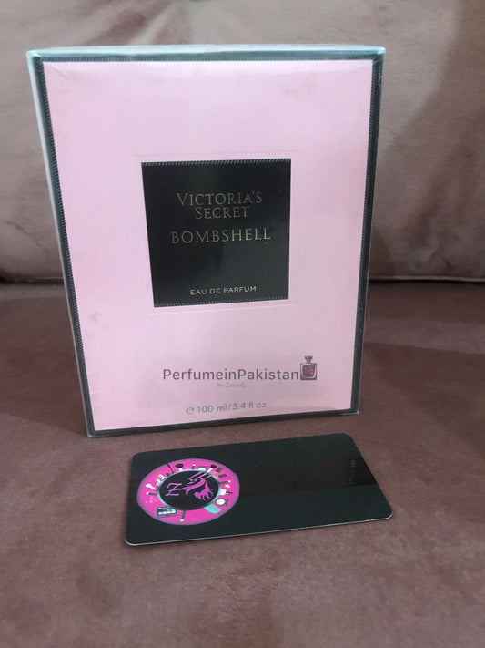 Victoria's Secret Bombshell Eau de Parfum 100ml perfume box displayed on pink velvet background with Perfume in Pakistan branding card