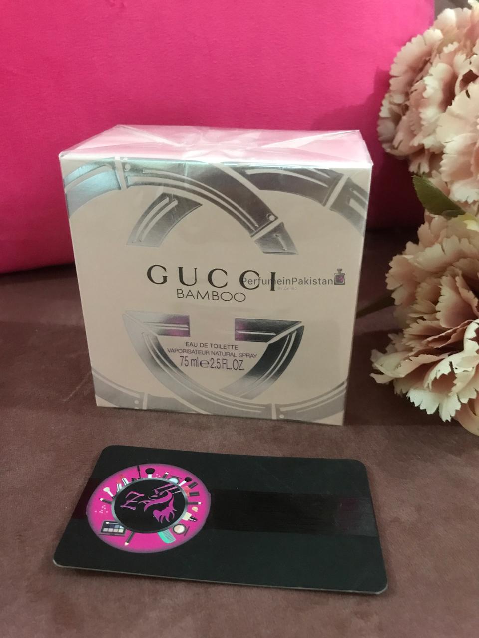 Gucci Bamboo Eau de Toilette 75ml perfume box displayed on a brown surface with floral decoration and PerfumeinPakistan branding card
