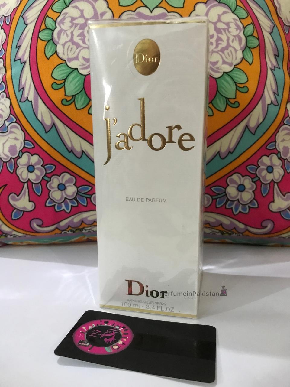 Dior J'adore Eau de Parfum 100ml perfume box displayed with decorative floral patterned background and PerfumeinPakistan branding card