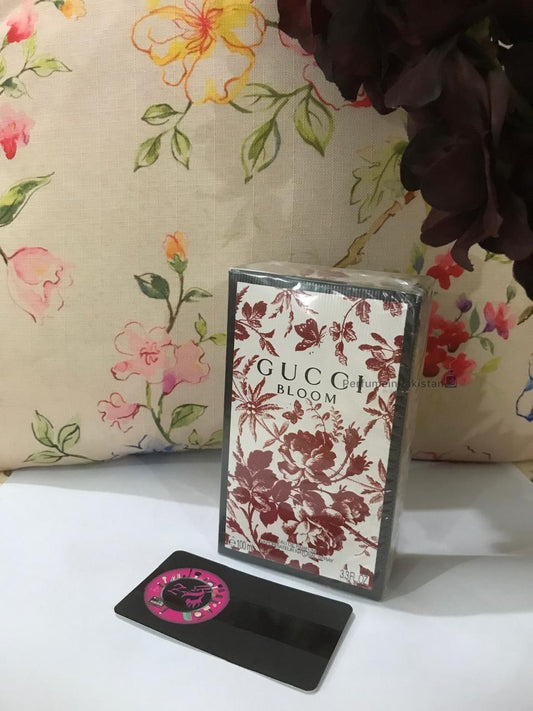 Gucci Bloom Eau de Parfum 100ml perfume box with floral artwork displayed against a floral background with PerfumeinPakistan branding card