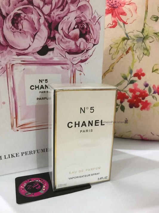 Chanel No. 5 Eau de Parfum 100ml perfume box displayed with floral Chanel-themed backdrop and PerfumeinPakistan branding card