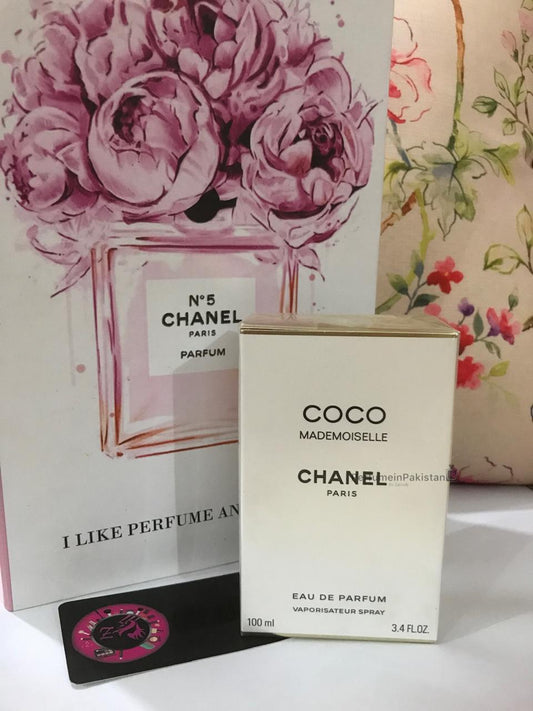 Chanel Coco Mademoiselle Eau de Parfum 100ml perfume box displayed with floral Chanel-themed backdrop and PerfumeinPakistan branding card