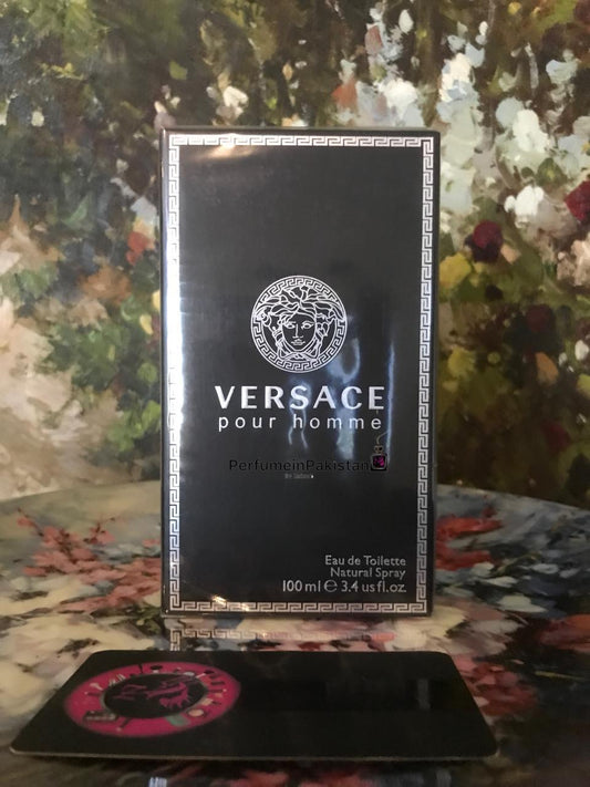 Versace Pour Homme by Versace Eau de Toilette for men in black 100ml packaging displayed with PerfumeinPakistan branding card against an artistic floral background.
