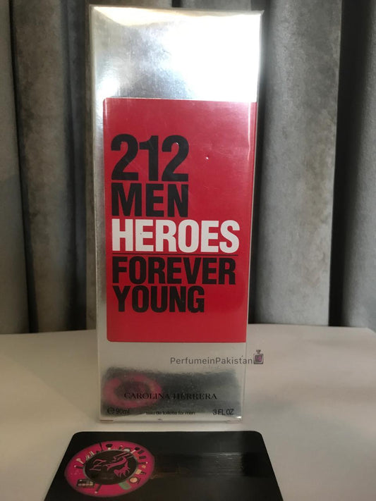 212 Men Heroes Forever Young by Carolina Herrera Eau de Toilette 90ml perfume box displayed with PerfumeinPakistan branding card on a white surface against a gray curtain background.
