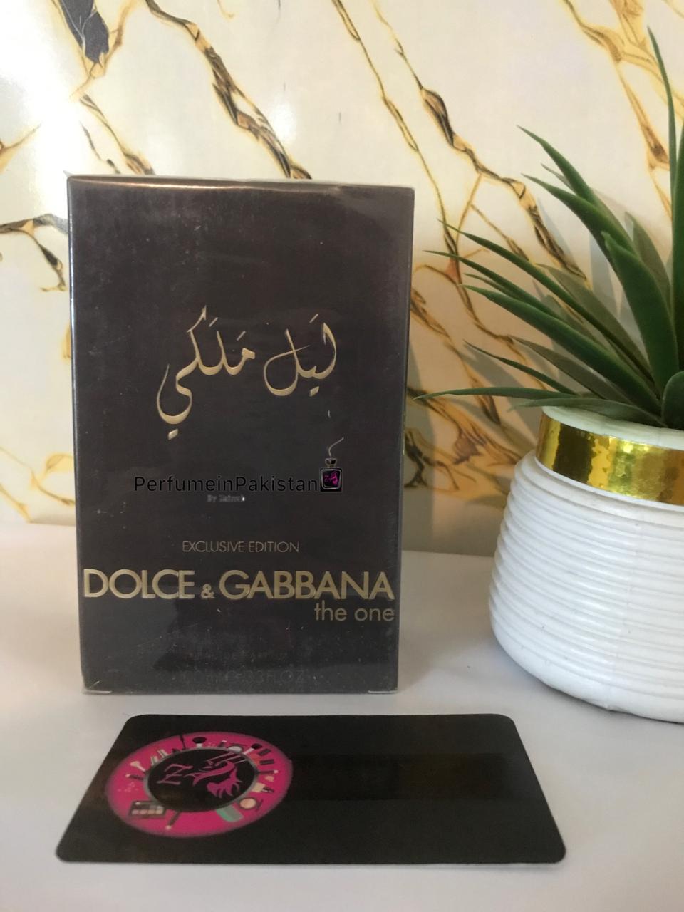 Dolce & Gabbana The One Exclusive Edition Eau de Parfum 100ml perfume box displayed beside a decorative green plant on a white surface with marble-pattern background and PerfumeinPakistan branding.