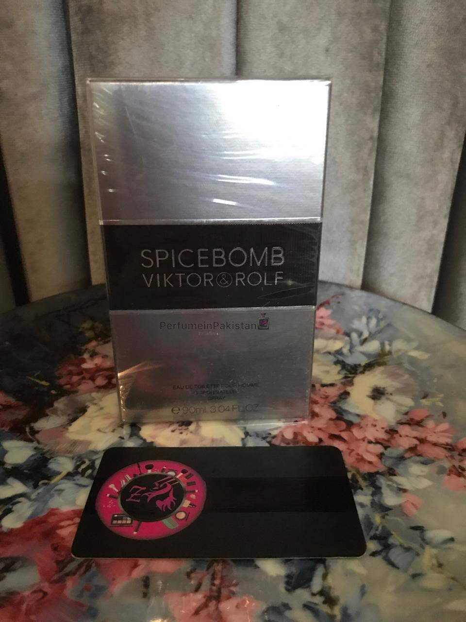 Viktor & Rolf Spicebomb Eau de Toilette 90ml perfume box displayed on a floral-pattern table with grey curtain background and PerfumeinPakistan branding.