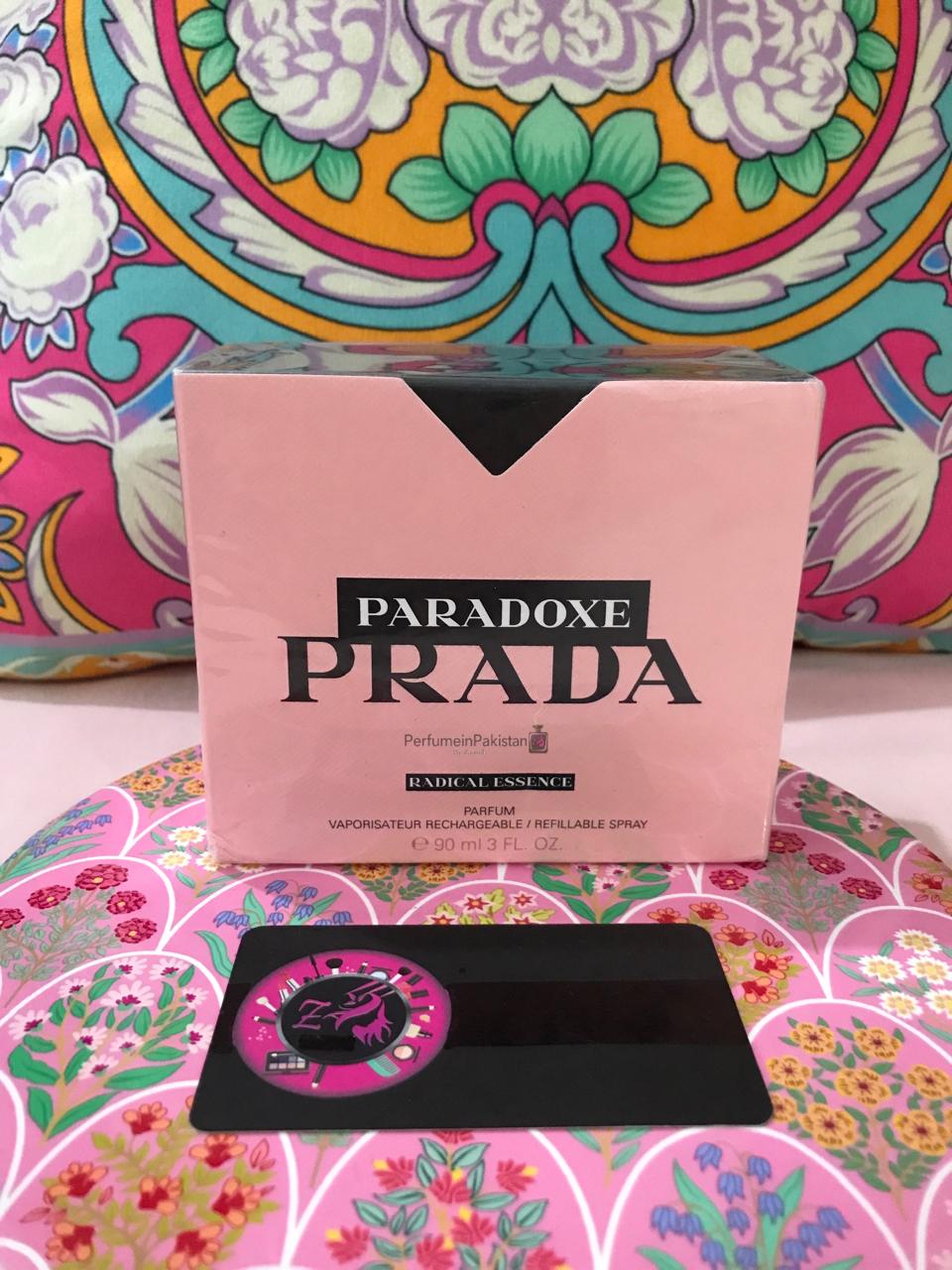 Prada Paradoxe Radical Essence Parfum 90ml perfume box displayed with Perfume in Pakistan by Zainab authenticity card on a decorative floral background.